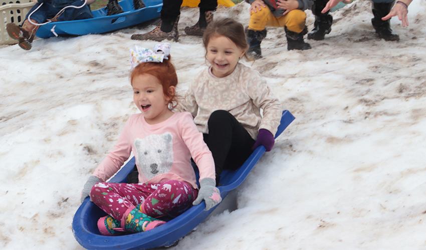 两个女孩从雪山上滑下来玩得很开心