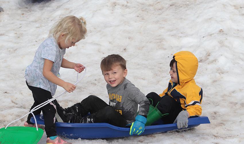 三个孩子从雪山上滑下来