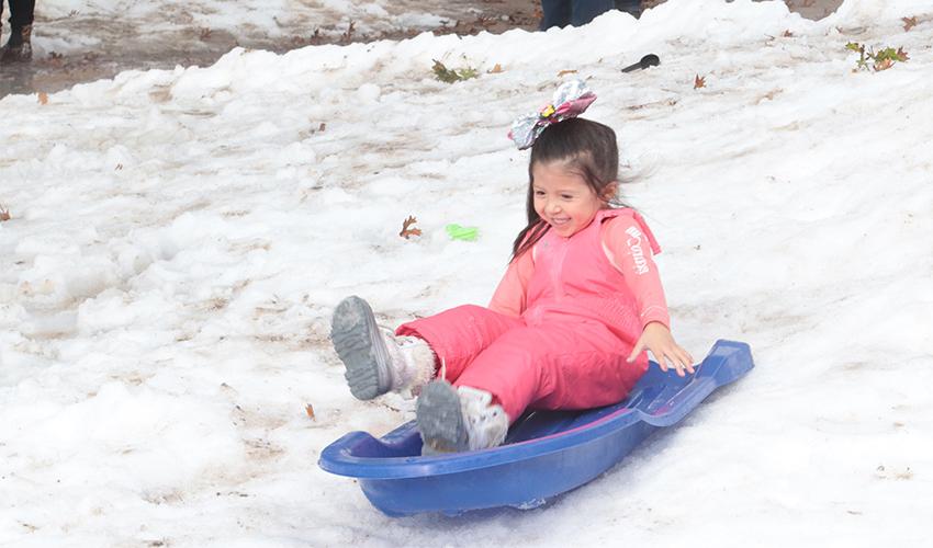 小女孩从雪山上滑下来